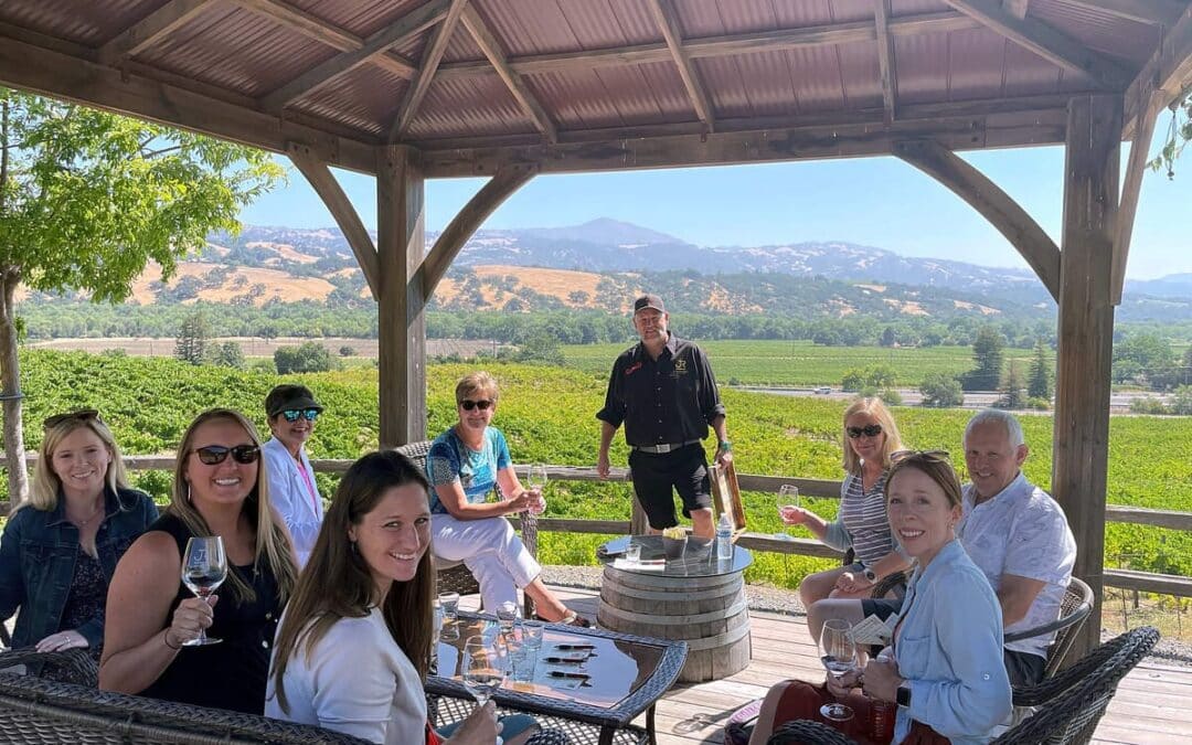 group of people sitting around wine tasting overlooking vineyards