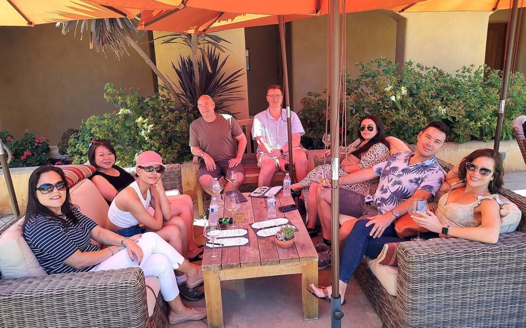 group of people sitting around a table wine tasting
