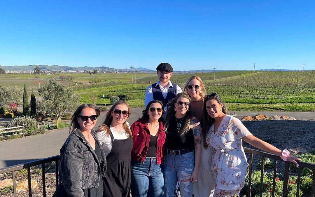group of people standing together with vineyards behind