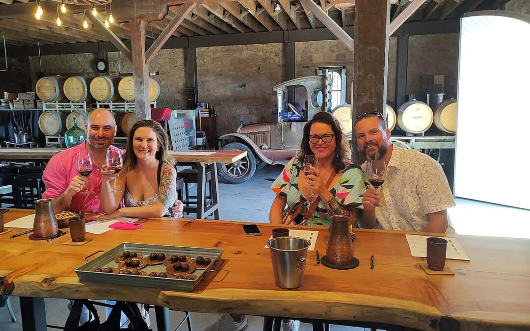 two couples sitting at table wine tasting