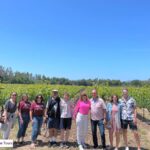 group of people standing in front of vineyards