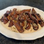 Roasted honey nut squash wedges arranged on a platter over a smooth white bean purée, topped with a toasted pumpkin seed and spice crunch.