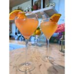 Pink grapefruit and rose Paloma cocktails in stemmed glasses with citrus garnish and rose salt rims on a marble countertop