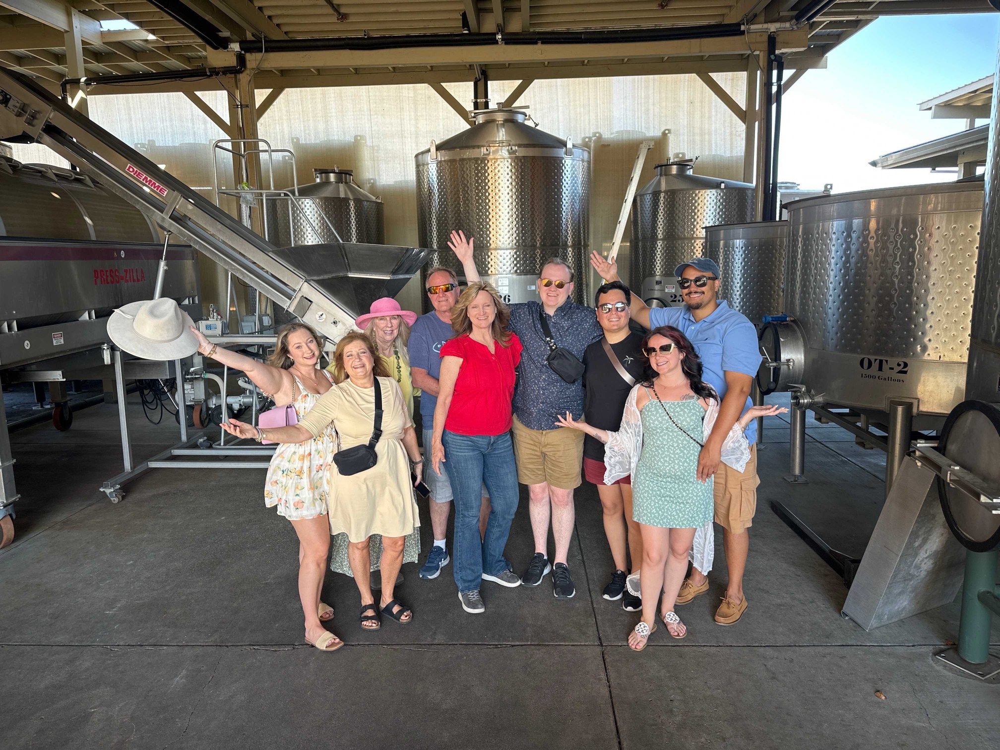 Platypus Wine Tours guests posing together among stainless steel fermentation tanks during a winery visit.