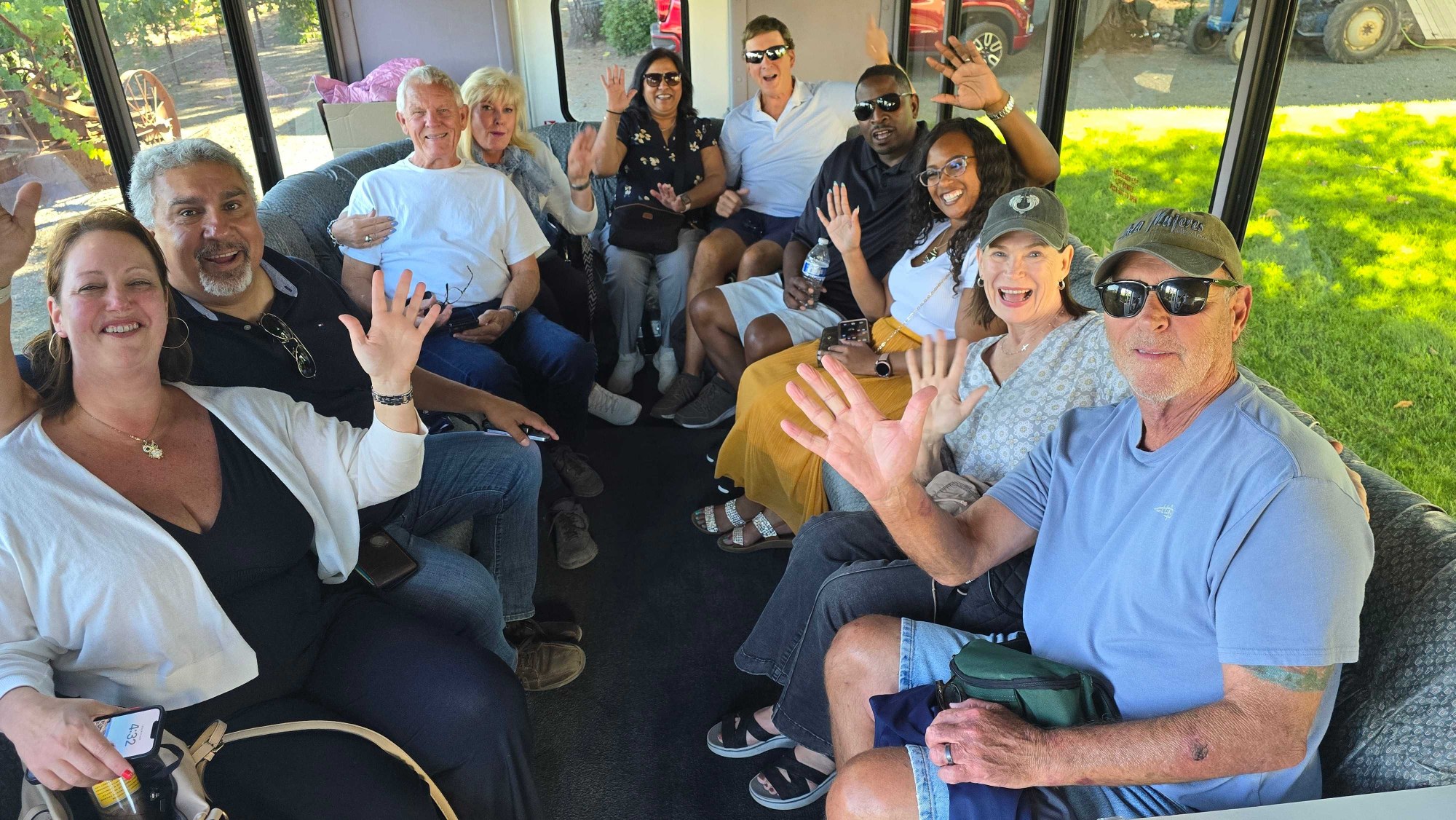 Platypus Wine Tours guests smiling and waving together inside a wine tour shuttle, enjoying a fun day in wine country.