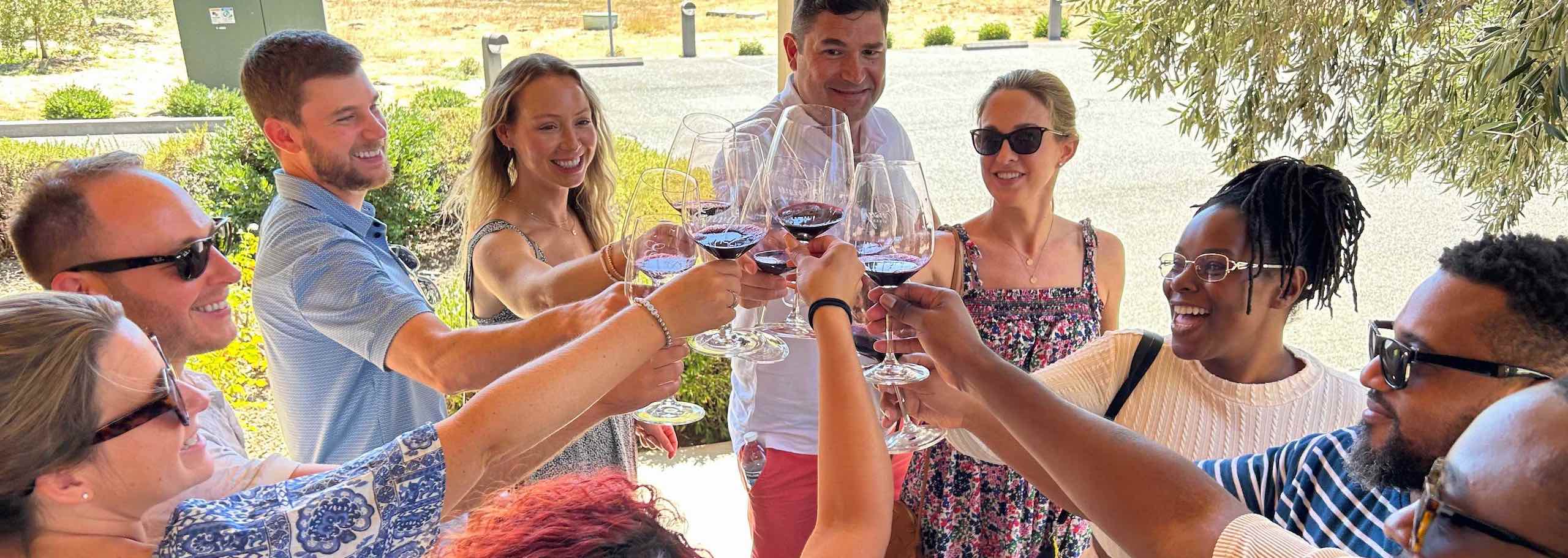 Platypus Wine Tours guests raising glasses of red wine for a toast during a winery tasting.