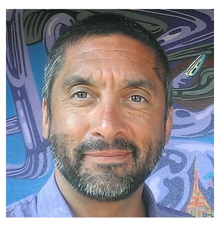 Portrait of Luis, a Platypus Wine Tours guide, smiling in front of a colorful mural background.