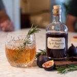 Homemade fig and rosemary shrub with fresh figs, rosemary and a cocktail served over ice.